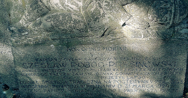 Fragment nagrobka, wykonany ze sztucznego kamienia, przedstawiający żołnierza półleżącego, pośród stylizowanych fal, wspartego o drzewce sztandaru zwieńczonego polskim orłem, fot. Adam Suwart