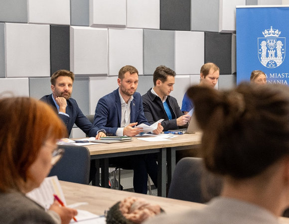 kilkoro osób w sali przy stole konferencyjnym - grafika artykułu