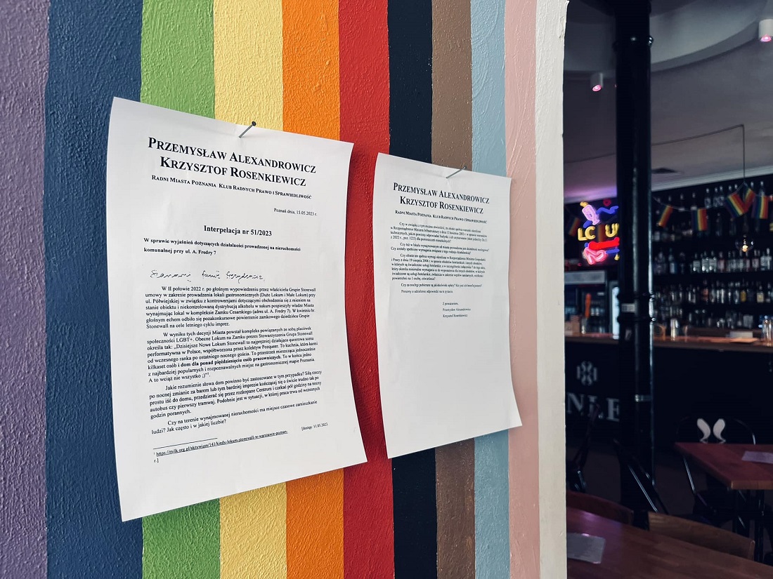 dwie zadrukowane kartki papieru zawieszone na ścianie w kolorach tęczy - grafika artykułu