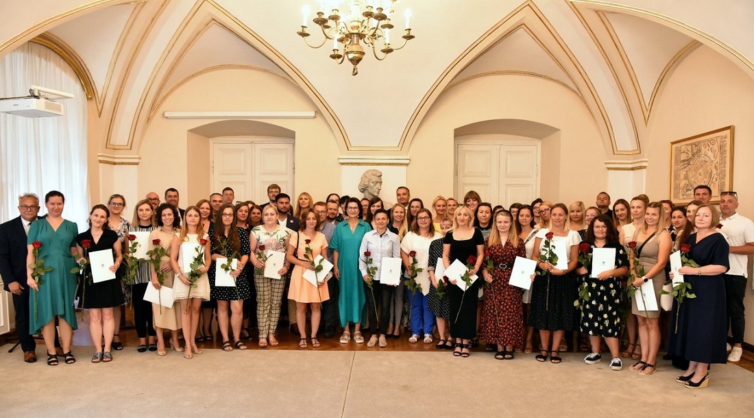 grupa osób kobiety i mężczyźni, pozujący do zdjęcia na tle białej sali - grafika artykułu