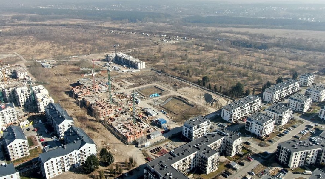 widok z lotu ptaka na teren częsciowo zabudowany blokami obok teren budowy a dalej teren niezabudowany - grafika artykułu