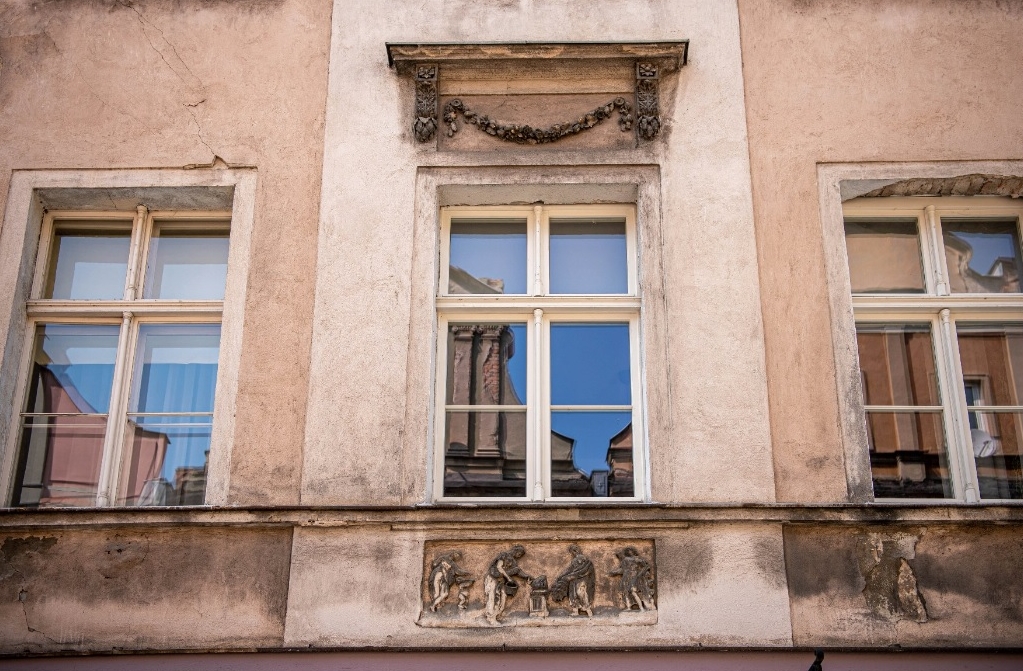 fragment fasady kamienicy, widoczne trzy okna na dużym zbliżeniu, widoczne zabrudzenia, ślady wilgoci i odpadającego tynku - grafika artykułu