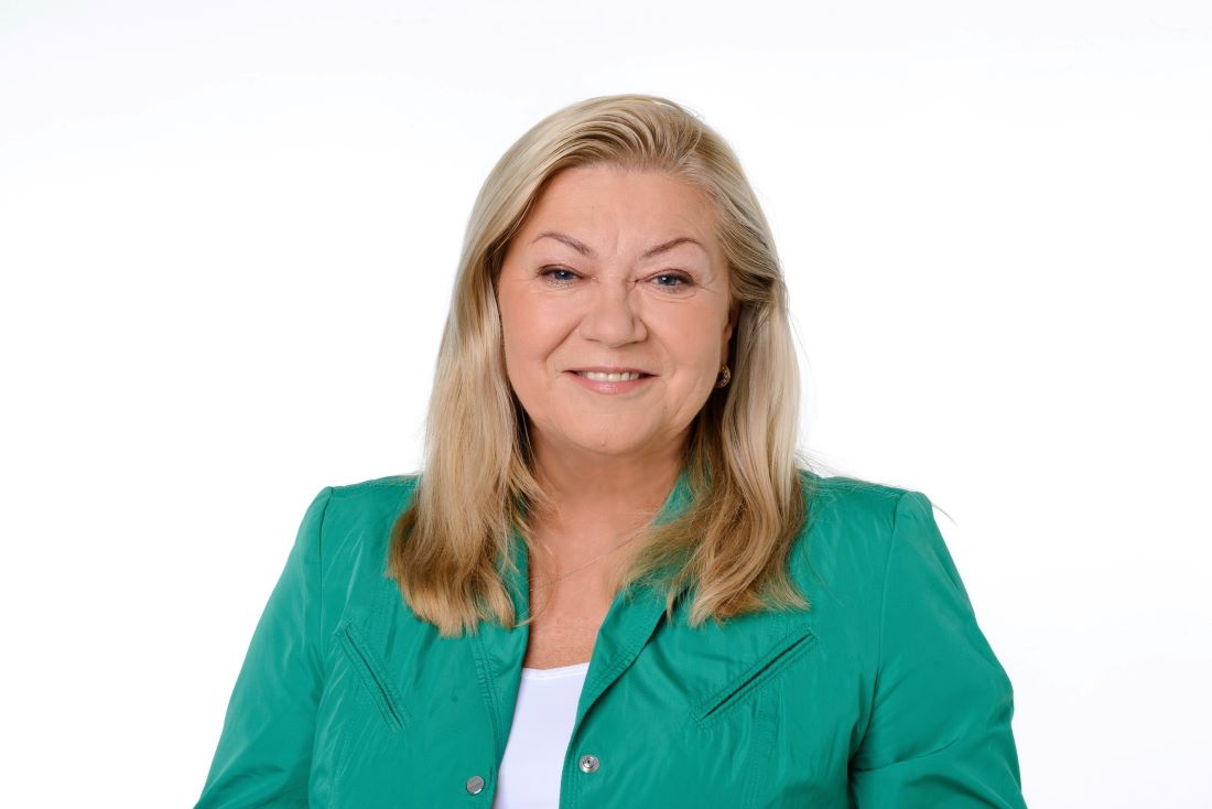 zdjęcie kobiety, która patrzy prosto w obiektyw, uśmiecha się, ma długi blond włosy, ubrana w kolorze zielonym - grafika artykułu