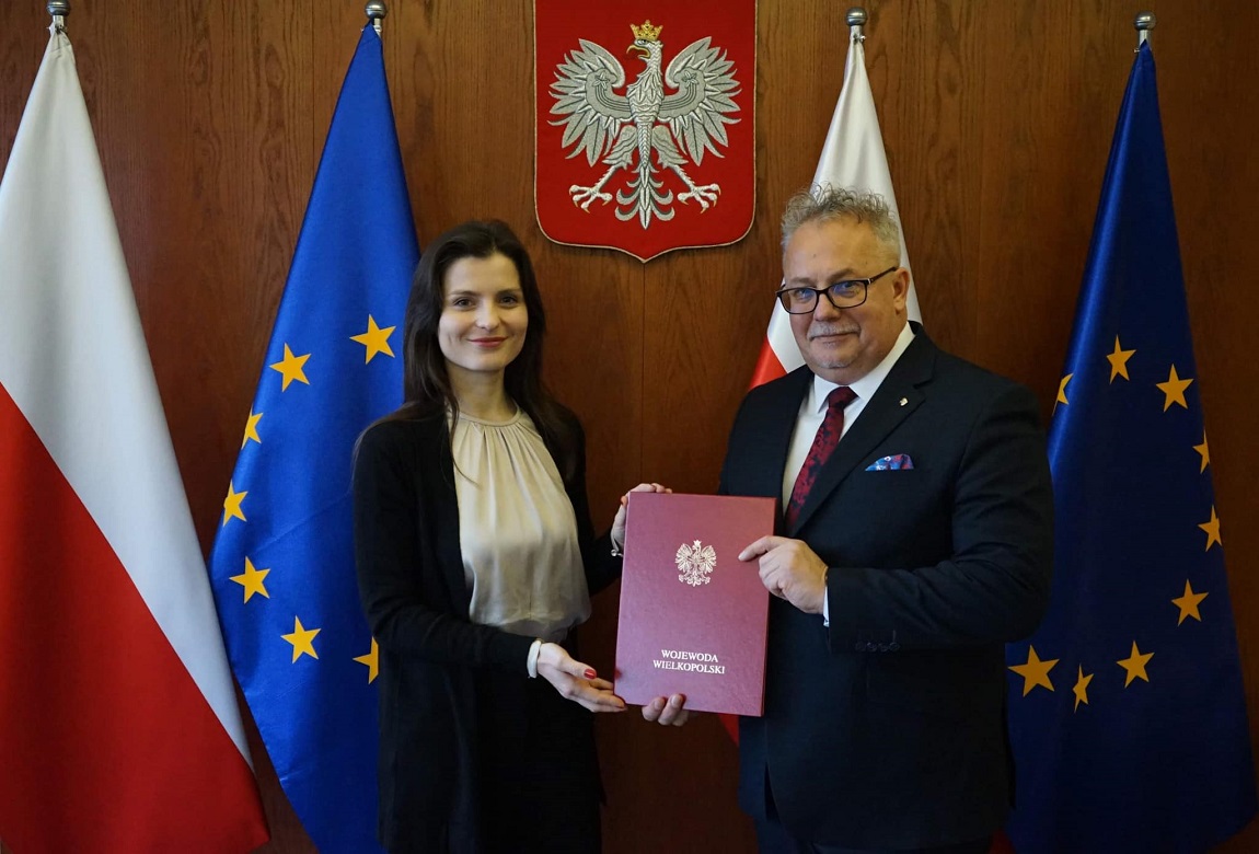 Wojewoda Wielkopolska Agata Sobczyk wręcza Wiesławowi Banasiowi nominację na stanowisko p.o. Wielkopolskiego Kuratora Oświaty, w tle flagi Polski i Unii Europejskiej - grafika artykułu