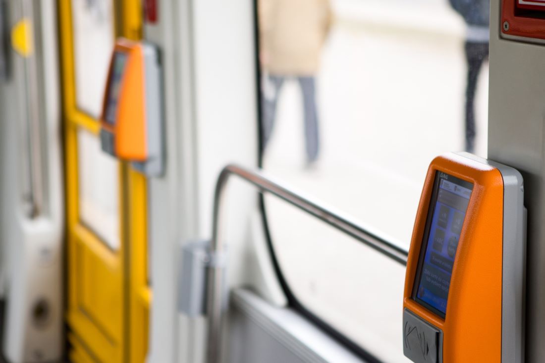 Fragment wnętrza tramwaju, widoczne kasowniki, poręcze, drzwi i okno - grafika artykułu