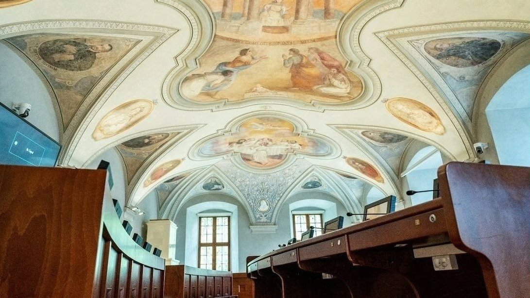 Sala sesyjna Rady Miasta Poznania, pusta, widoczne stanowiska radnych i zdobiące sufit zabytkowe freski