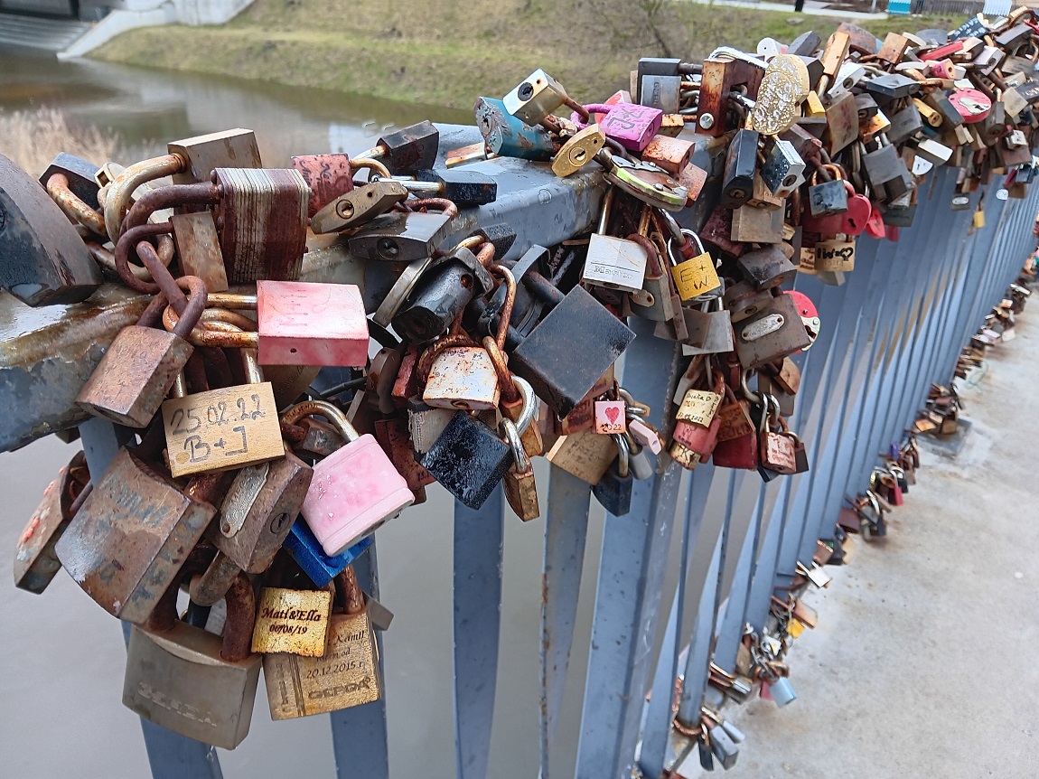 duża ilośc kłódek zapiętych na balustradzie mostu, gęsto jedna przy drugiej - grafika artykułu