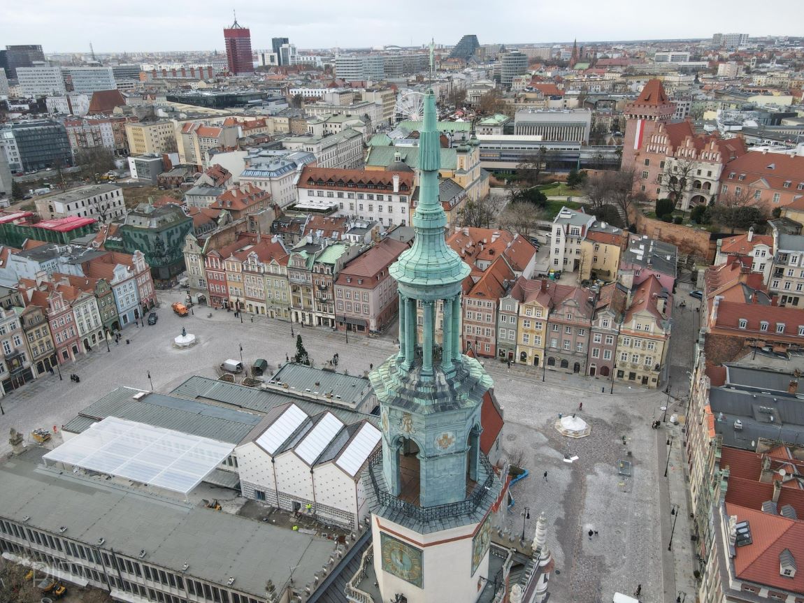 widok z lotu ptaka na fragment starego Rynku w Poznaniu, na pierwszym planie wieża Ratusza, dalej za płytą rynku widoczny zamek Przemysła i częściowo plac Wolności - grafika artykułu