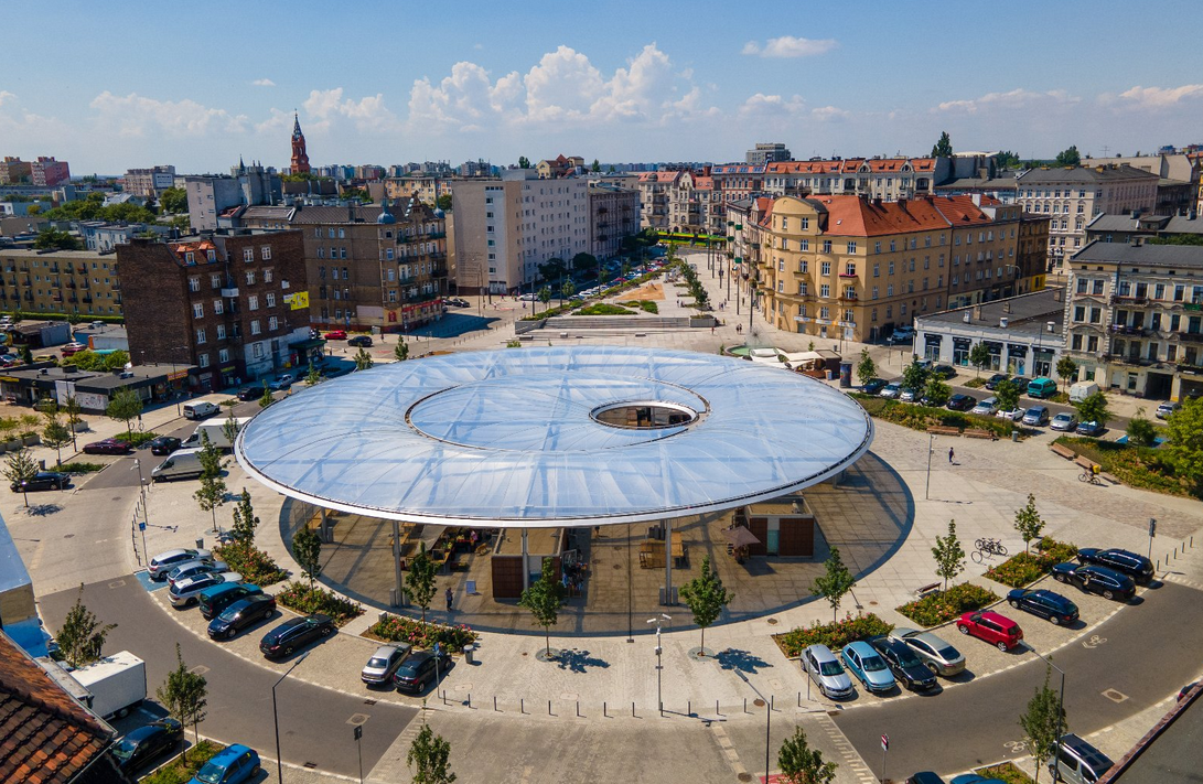 widok z lotu ptaka na Rynek Łazarski, charakterystyczne zadaszenie w formie talerza, wodoczne kamienice i inne zabudowania wokół rynku - grafika artykułu