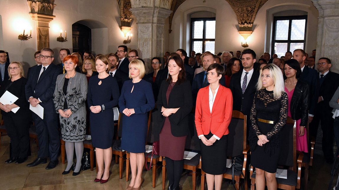 grupa osób kobiet i mężczyzn stojąca w rzędacg w sali z zabytkowymi zdobieniami