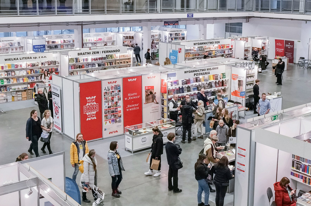 hala targowa ze stoiskami z książkami, w hali wiele osób - grafika artykułu