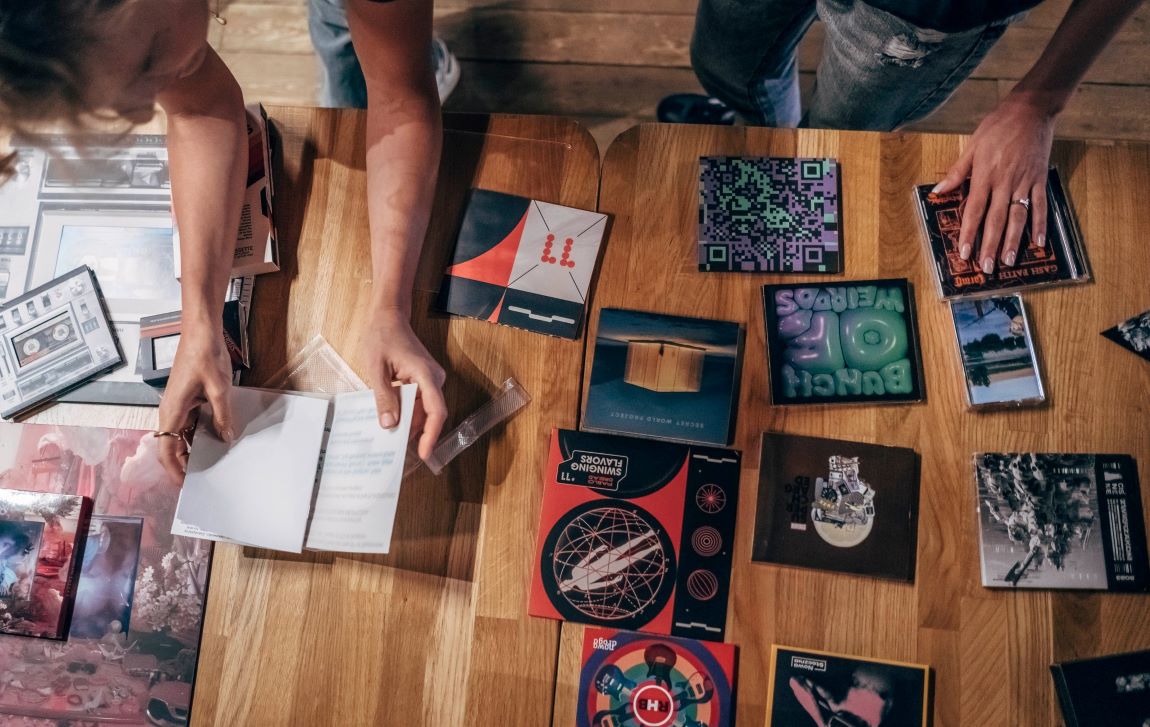 na stole rozłożonych jest około kilkanaście różnych okładek płytowych - grafika artykułu