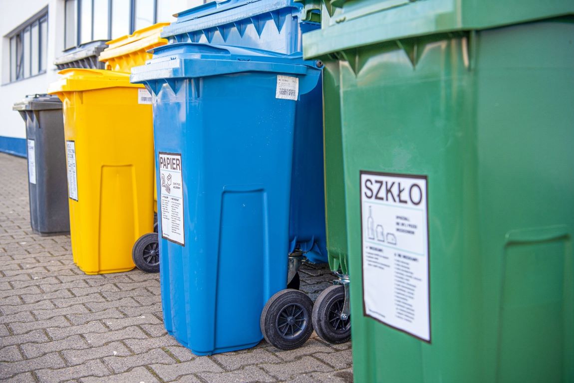 przed budynkiem wystawione cztery kontenery na odpady: szkło, papier, tworzywa sztuczne i zmieszane - grafika artykułu