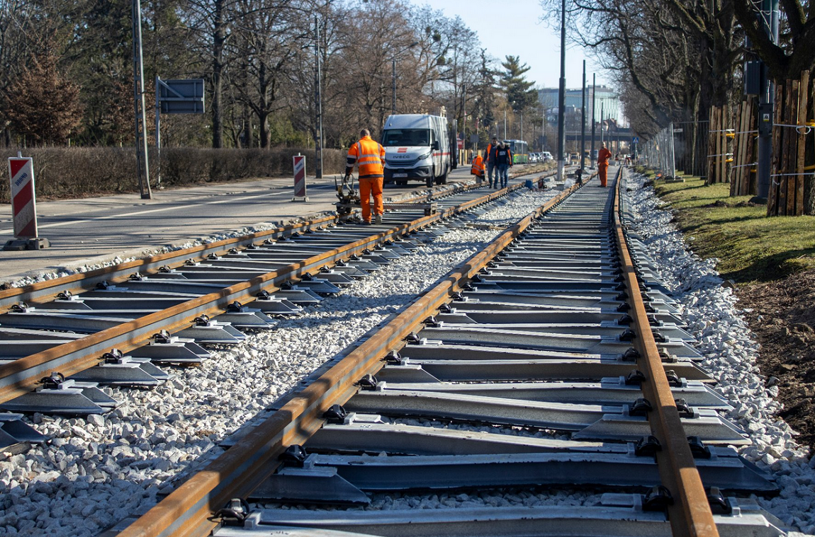 ekipa remontowa prowadzi prace na torowisku tramwajowym położonum w alei wśród drzew - grafika artykułu