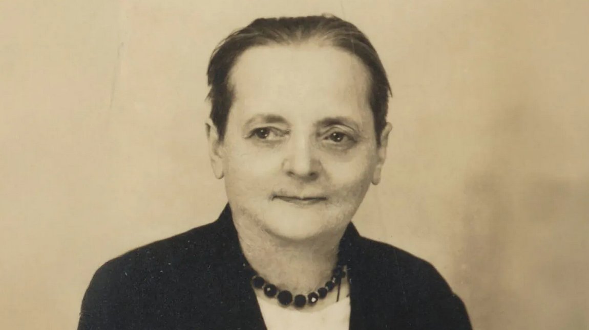 archiwalne zdjęcie kobiety w średnim wieku, w czarnym ubraniu, włosy zaczesane do tyłu i upięte