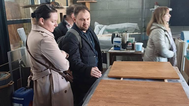 kilkoro osób zwiedza pomieszczenie warsztatu rzemieślniczego, na stołach rozłożone deski