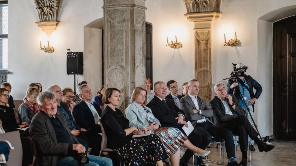 publiczność w sali ratusza, duża liczba ludzi siedzących na krzesłach w wielu rzędach