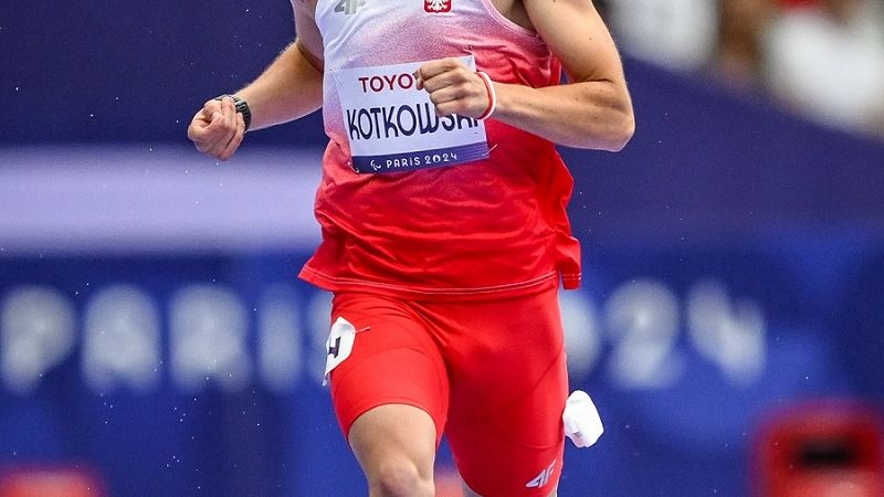 Michał Kotkowski (zawodnik) - Nagroda Sportowa Miasta Poznania 2025 - sportowiec ubranu w strój sportowy reprezentacji polski, biegnie na wprost, jest uśmiechnięty