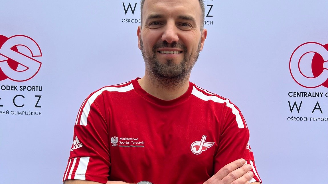 Krzysztof Rachwalski (trener) - Nagroda Sportowa Miasta Poznania 2025 - mężczyzna ubrany w t-shirt, z założonymi rękoma, ma lekki zarost, uśmiecha się