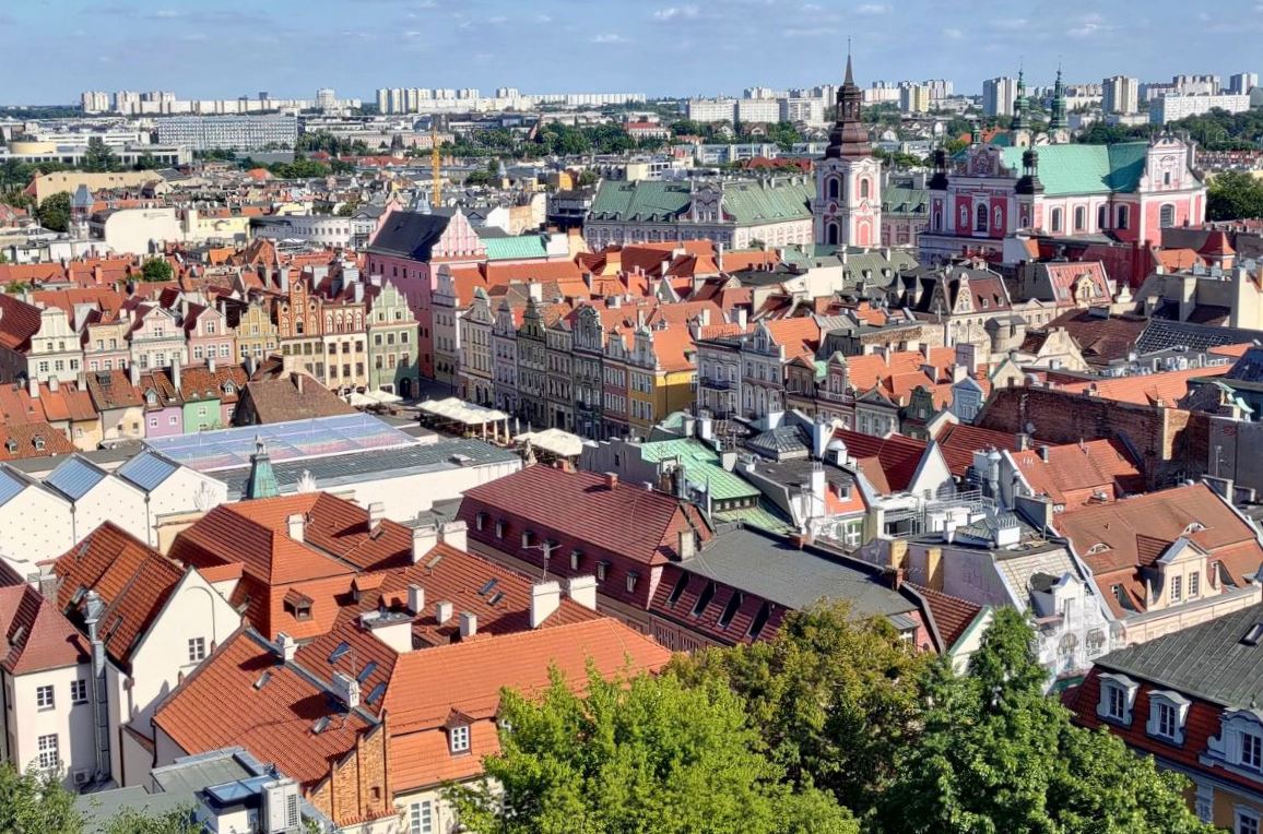 panorama miasta z lotu ptaka, na pierwszym planie zabudowa śródmiejska, wąskie kamienice ze spadzistymi dachami, widać wieże kościelne, na dalszym planie nowe budynki, bloki mieszkalne, biurowce, wieżowce - grafika artykułu