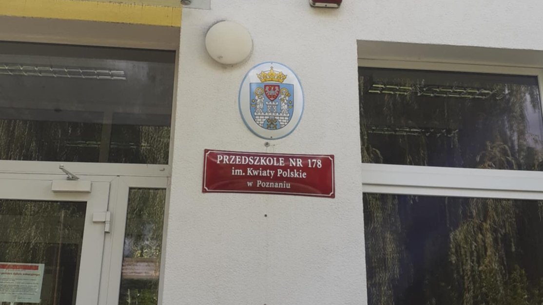 przed wejściem do przedszkola na ścianie herb Poznania i tablica z nazwą przedszkola