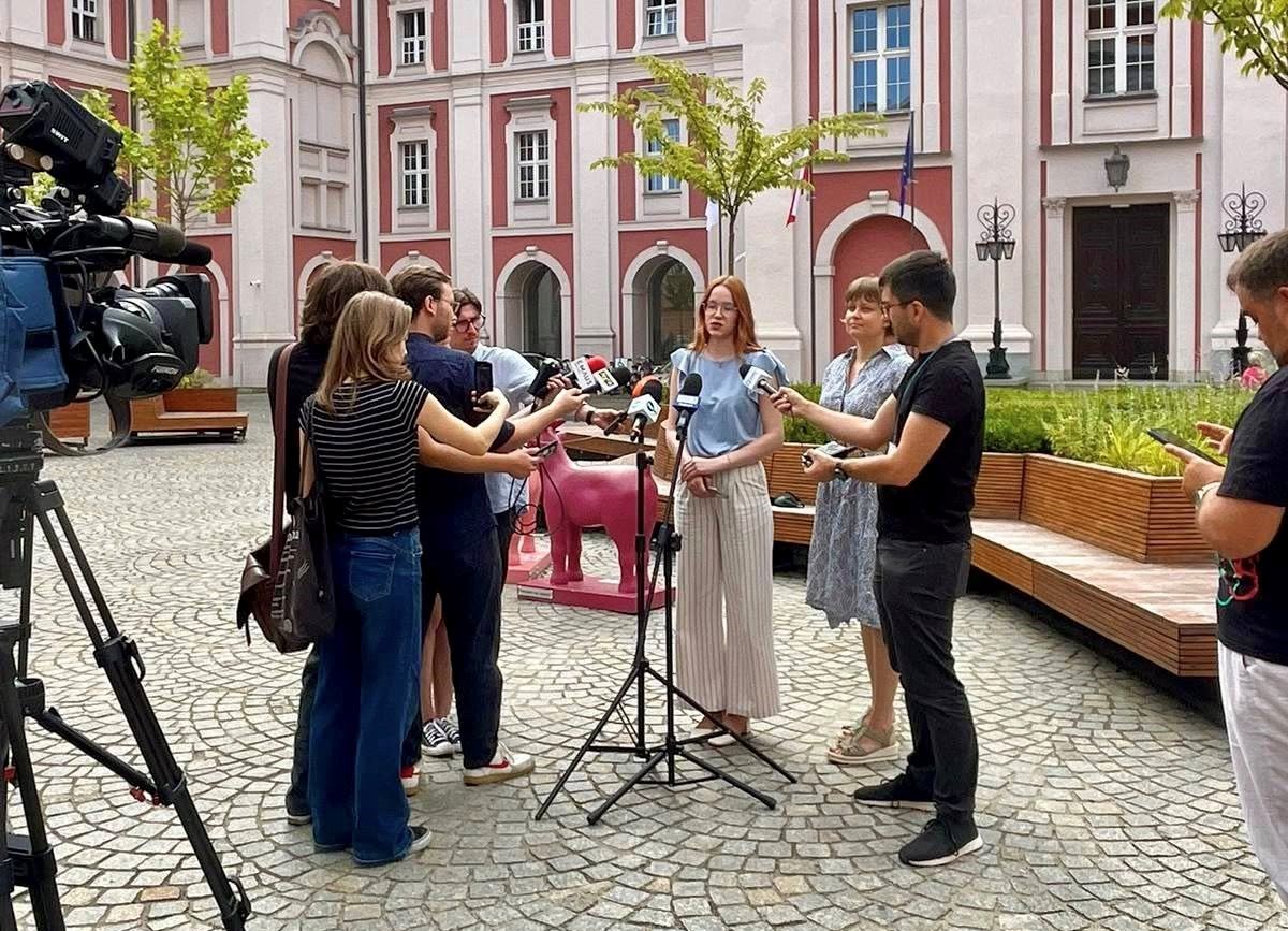 konferencja prasowa na dziedzińcu urzędu miasta, osoby stroją przed mikrofonem, przed nimi media z mikrofonami i kamerami - grafika artykułu
