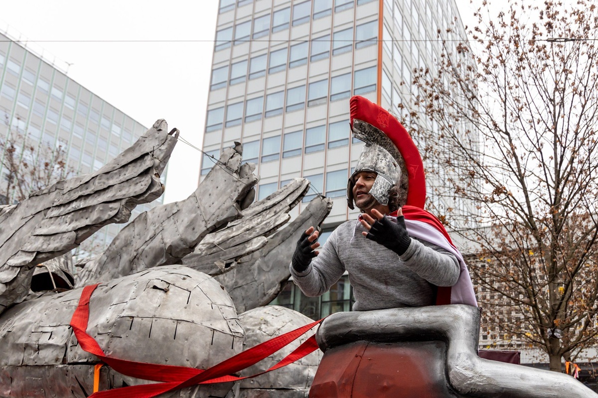 mężczyzna w stroju rzymskiego legionisty podczas korowodu świętomarcińskiego jest na podwyższeniu za nim widać fragment wieżowców przy ulicy - grafika artykułu