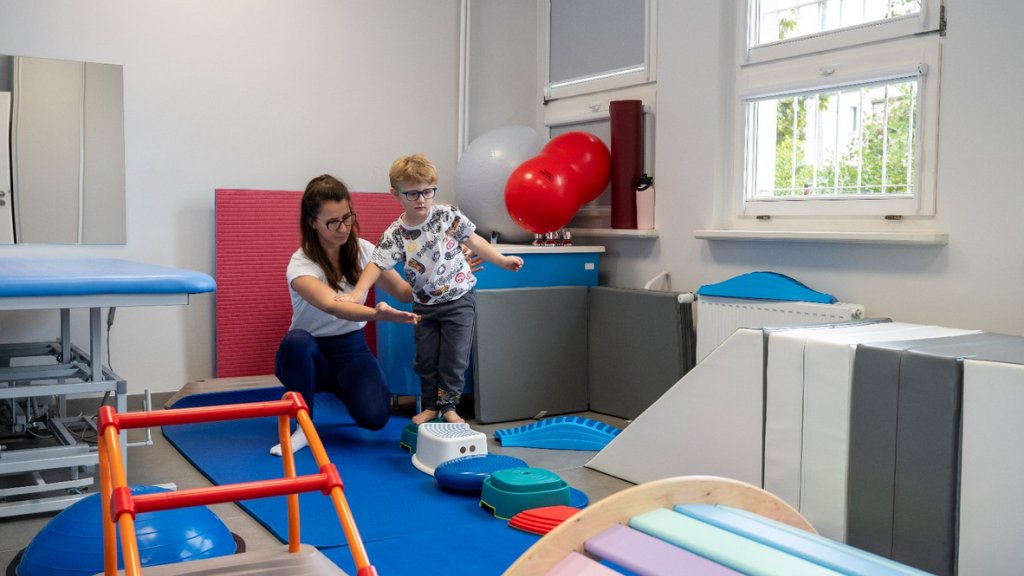 Sala dla terapii dzieci dziecko przy pomocy opiekunki korzysta z urządzeń w sali