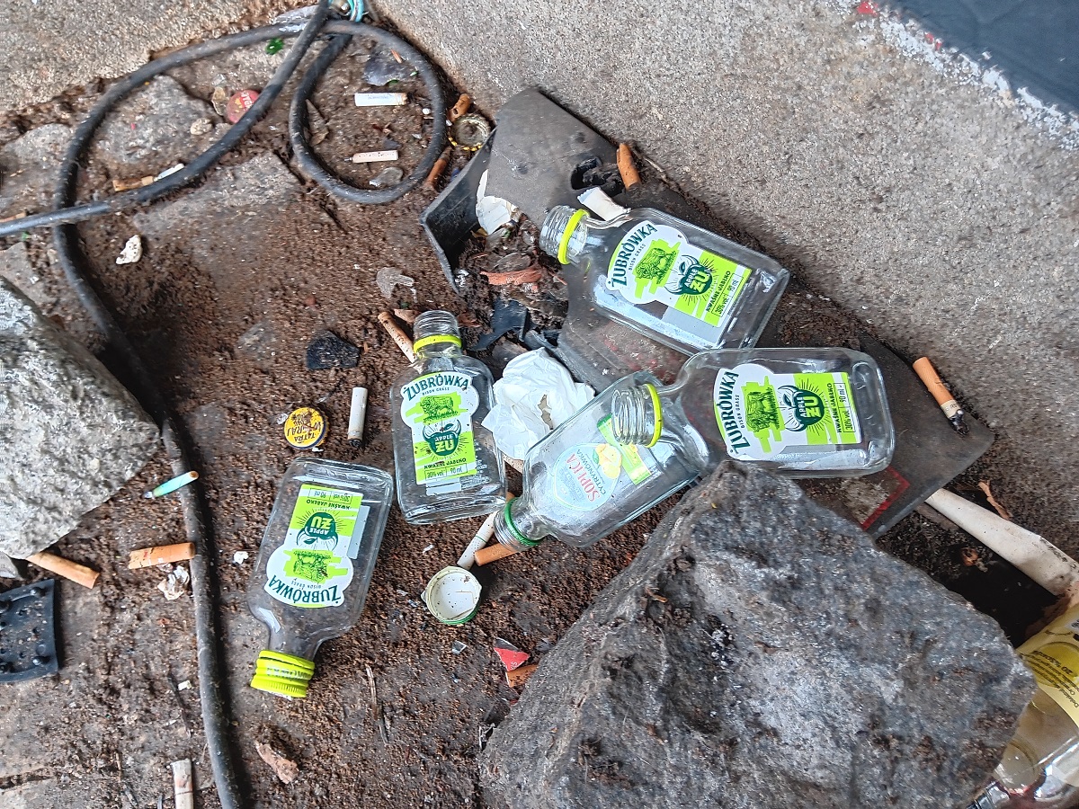 kilka małych butelek po alkoholu pustych pozostawionych na chodniku - grafika artykułu