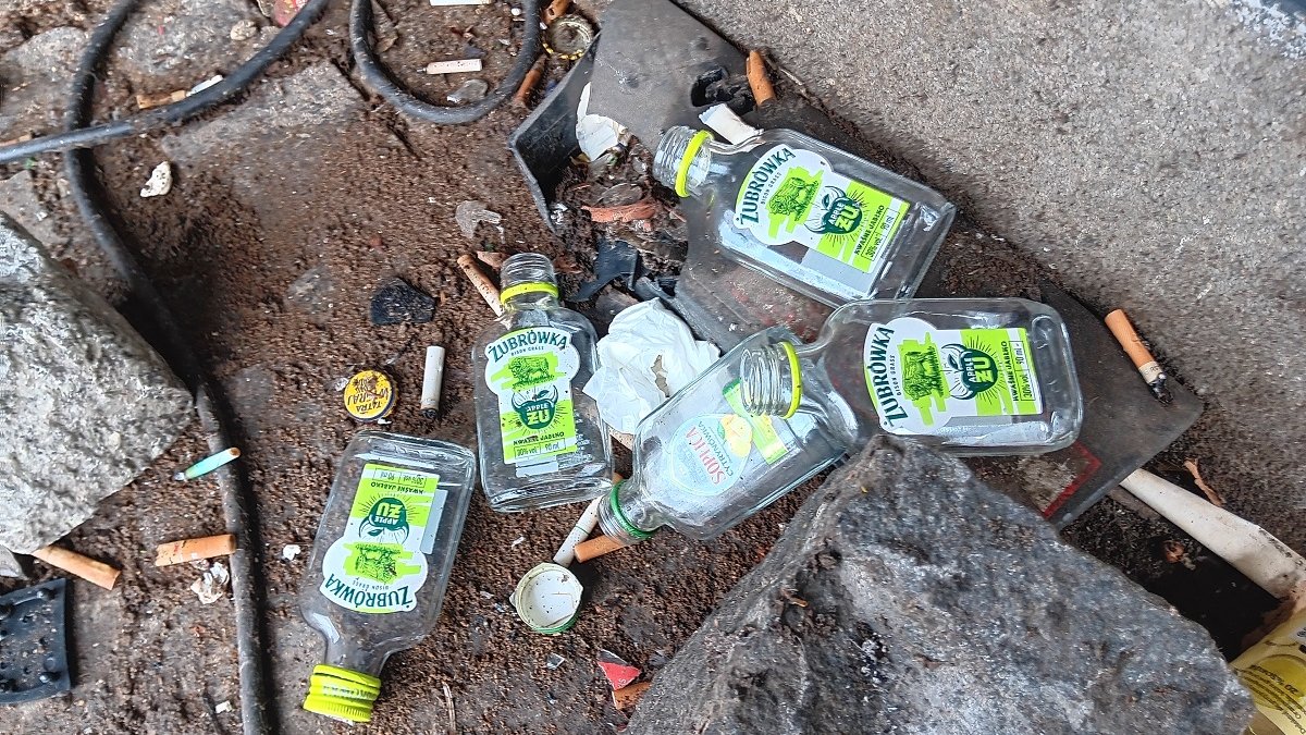 kilka małych butelek po alkoholu pustych pozostawionych na chodniku