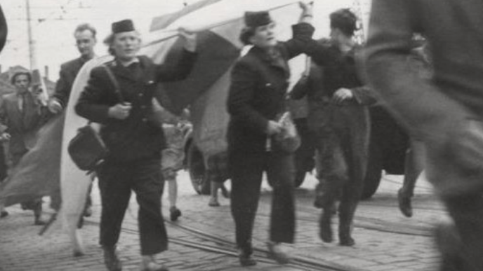 trzy kobiety w mundurach trwamwajrek idą w tłumie niosąc flagę lub transoparent - archiwalne zdjęcie tramwajarek Stanisławy Sobańskiej, Heleny Przybyłek i Marii Kapturskiej