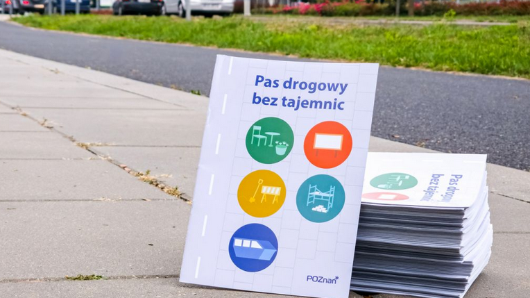 broszury ułożone na chodniku, na okładce tytuł "Pas drogowy bez tajemnic"
