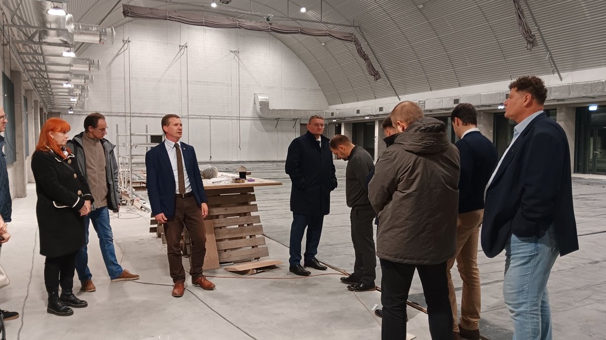 grupa osób w hali sportowej, której budowa jest na ukończeniu