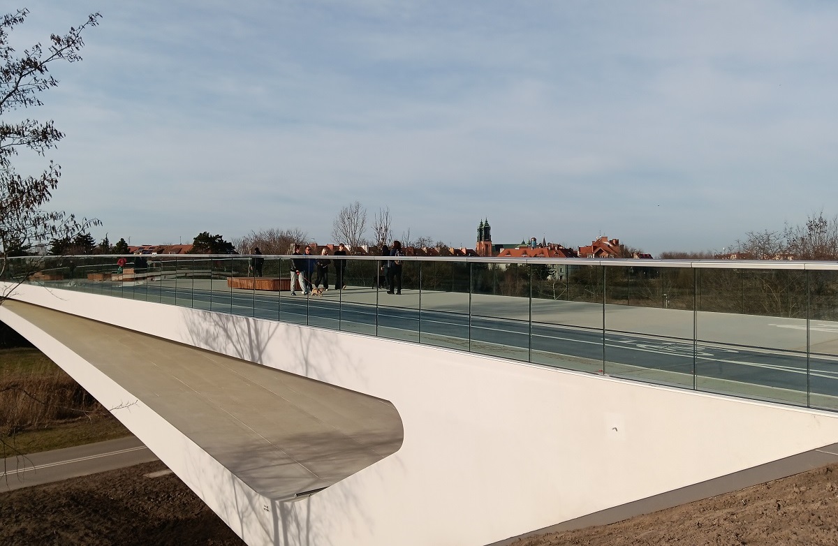 most pieszo rowerowy nad rzeką, ma szklane przejżyste balustrady na moście spacerują ludzie - grafika artykułu