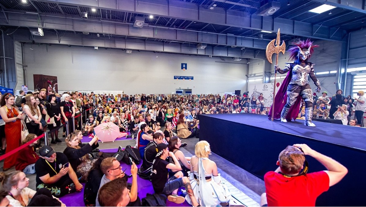 na scenie w dużej sali osoba przebrana w strój z gatunku fantastyki, przed sceną siedzi mnóstwo osób, wiele z nich także przebranych w postaci fantastyczne - grafika artykułu