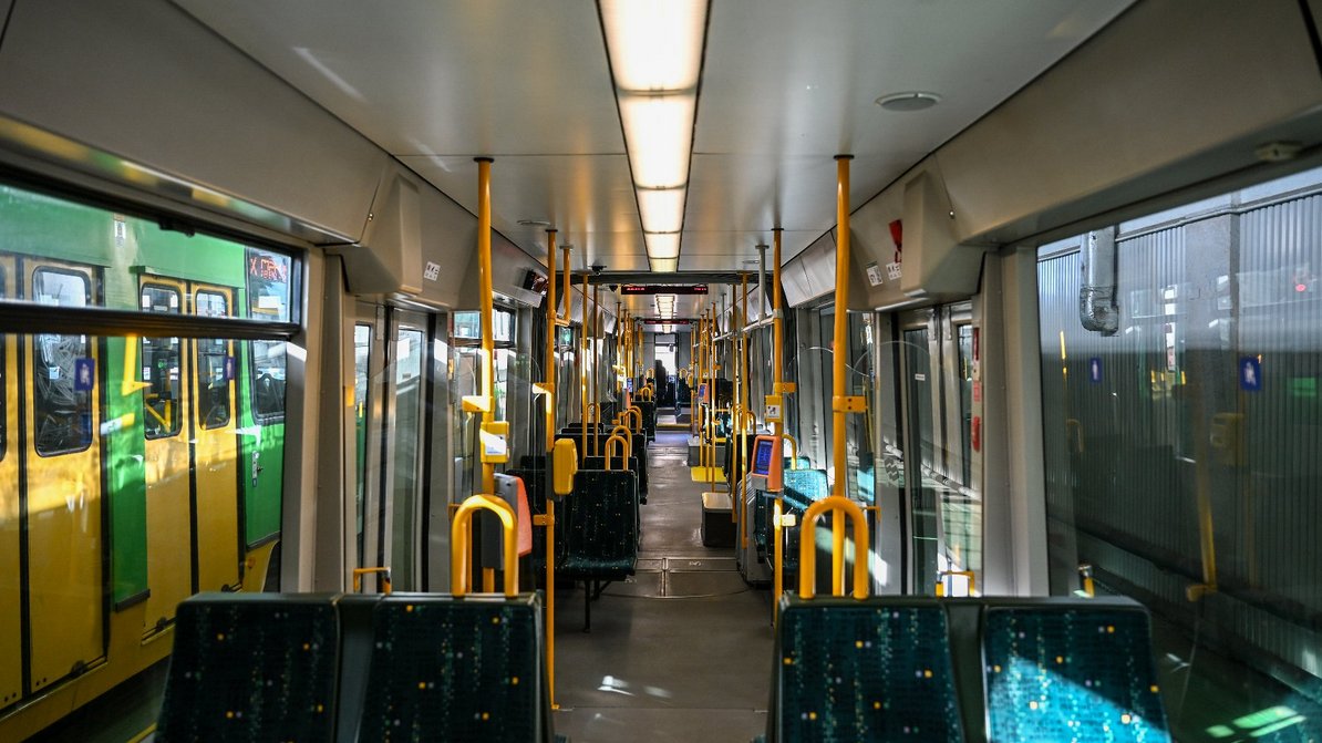 środek tramwaju, widoczne siedzenia, kasowniki i uchwyty