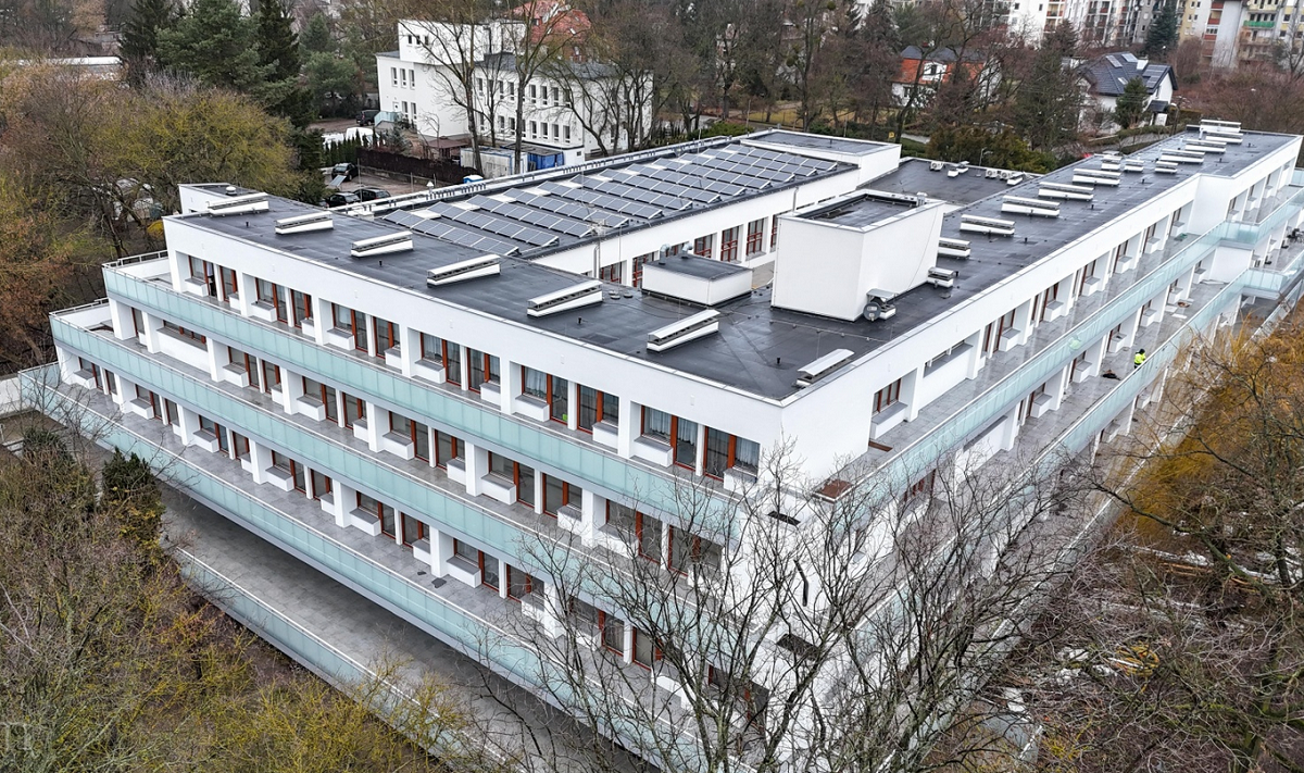 widok z lotu ptaka na kilkupietrowy budynek otoczony gęstą zielenią - grafika artykułu