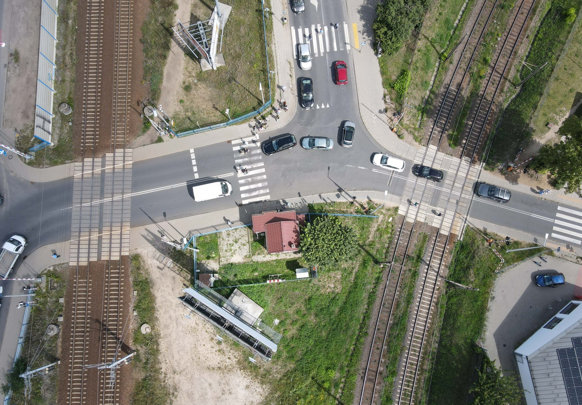 widok z góry na podwójny przejazd kolejowy, przez tory przejeżdżają samochody - grafika artykułu