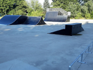 oddkryty skatepark z obiektami do uprawiania tych dyscyplun sportu, wokół obiketu drzewa i krzewy