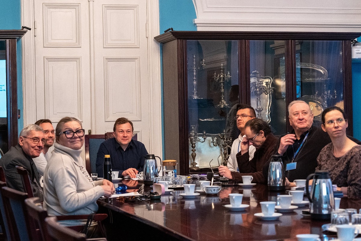 Przy stole konferencyjnym obraduje kilka osób, kobiet i mężczyzn w różnym wieku