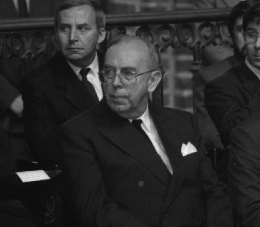 zdjęcie archiwalne starszego mężczyzny w garniturze siedzącego na krześle w kościele, obok niego inni mężczyźni