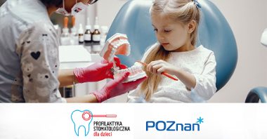 Grafika przedstawia dziewczynkę na fotelu stomatologicznym oraz stojącą obok dentystkę. Dziecko czyści szczoteczką model szczęki.