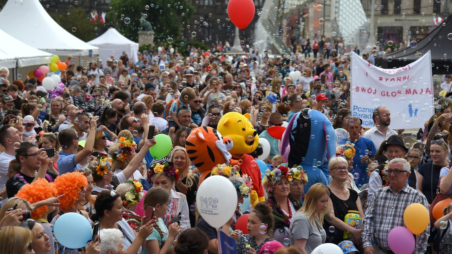 Na zdjęciu Parada Pokoleń, która kończyła Poznańskie Dni Rodziny 2019 - widać dużo uśmiechniętych ludzi, niosą balony, puszczają bańki mydlane - grafika artykułu