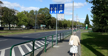 Ulica Przybyszewskiego i chodnik, po którym idzie starsza pani