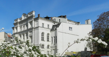 Zdjęcie Teatru Polskiego, na pierwszym planie krzak z białymi kwiatami