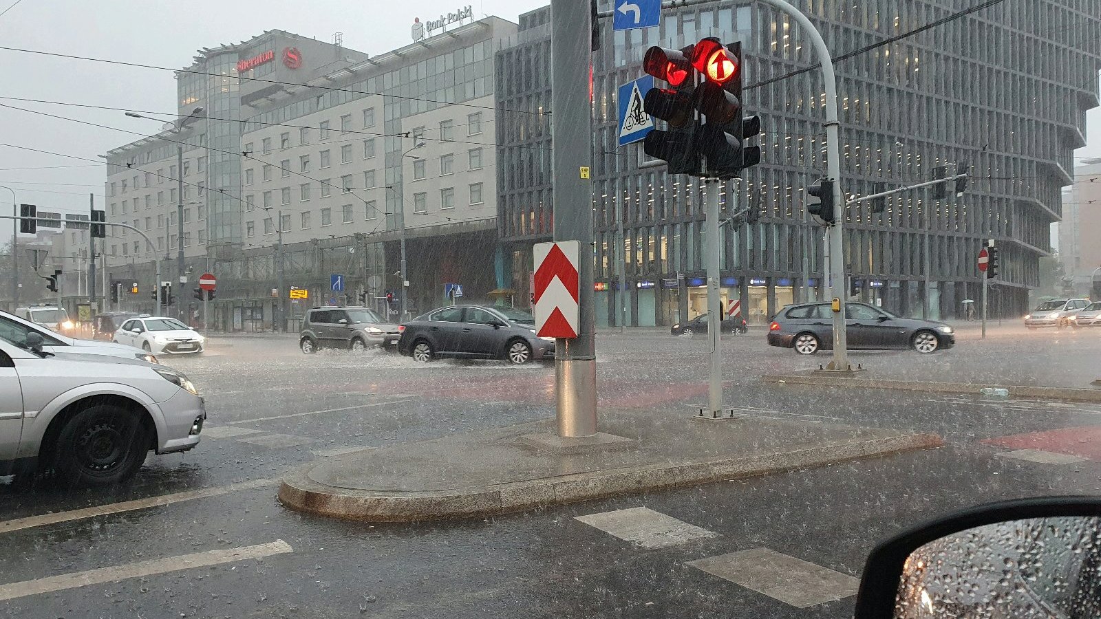 Zdjęcie przedstawia ulicę w deszczu. Widać na nim samochody i budynki. - grafika artykułu