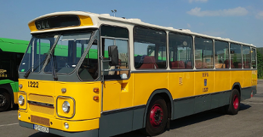 Zdjęcie przedstawia zabytkowy żółty autobus.