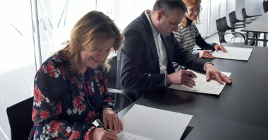Na zdjęciu trzy osoby podpisujące dokument