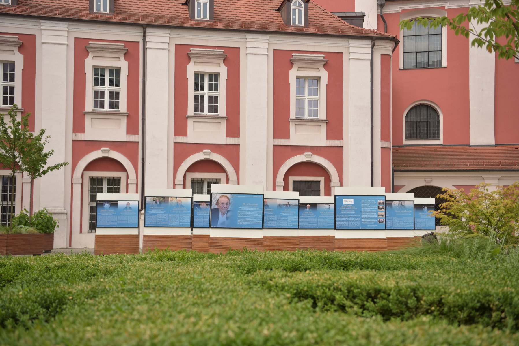 Od wtorku, 17 czerwca na Wolnym Dziedzińcu przy placu Kolegiackim można oglądać wystawę "Twarze Poznania. Honorowi i zasłużeni 1920-2025" Zdjęcie przedstawia fragment wystawy i oglądającego ją mężczyznę. Stoi on tyłem do aparatu.