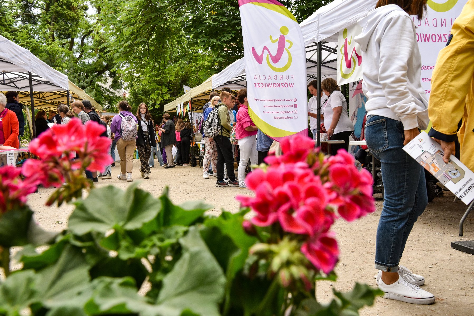 Ideą "Inicjatorów" jest uhonorowanie najciekawszych inicjatyw pozarządowych organizowanych na rzecz Poznania i jego mieszkańców Zdjęcie przedstawia tłum ludzi na stoiskach w parku. Na pierwszym planie widać kwiaty.